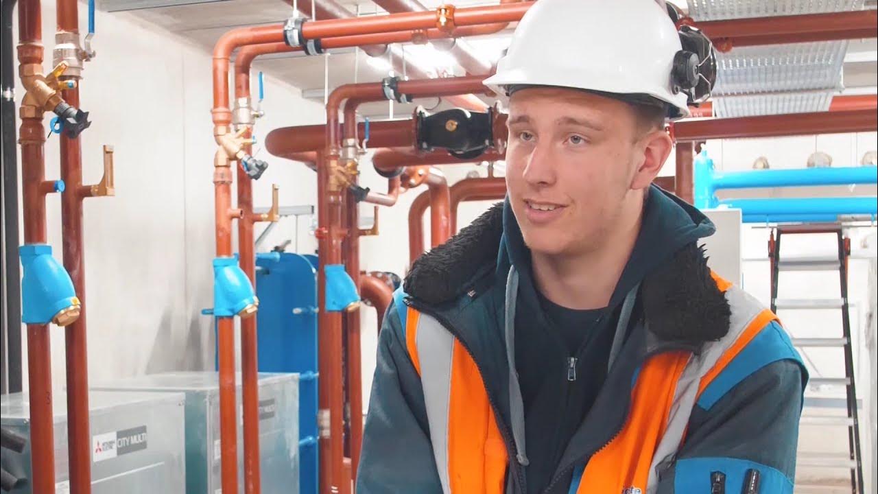 Monteur met helm in een technische ruimte met koperen leidingen