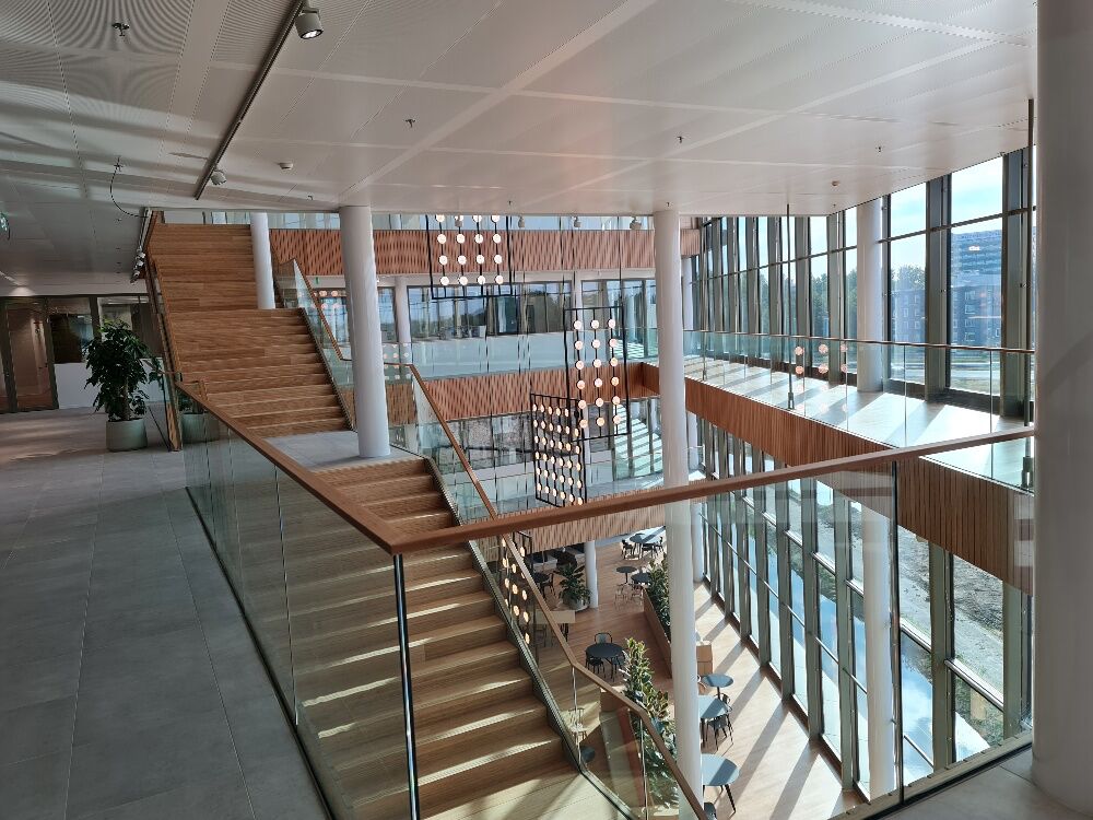 Trappenhuis met houten treden en glazen balustrade in het atrium