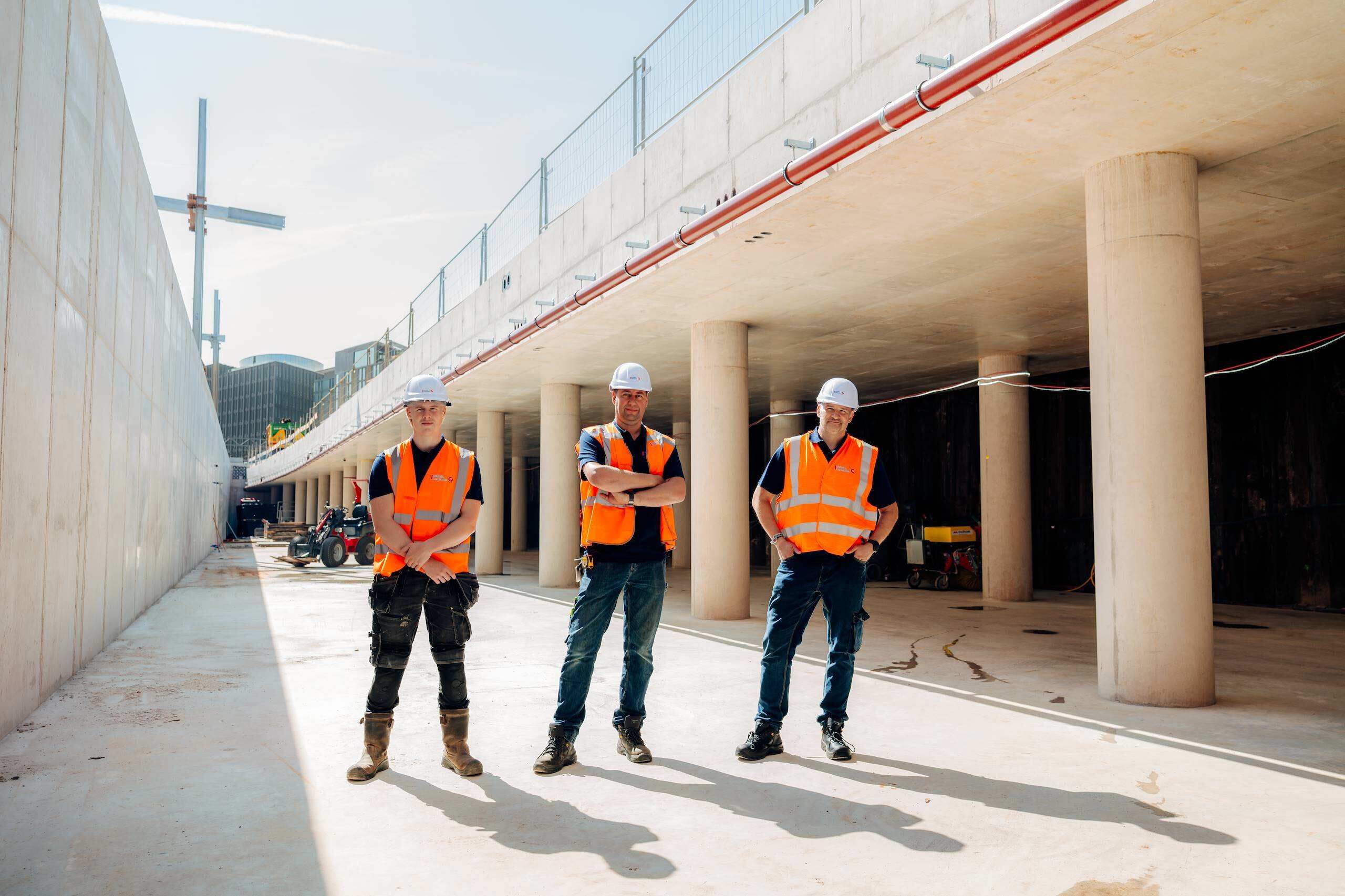 Drie monteurs van Schulte & Lestraden in veiligheidshesjes in een betonnen parkeergarage