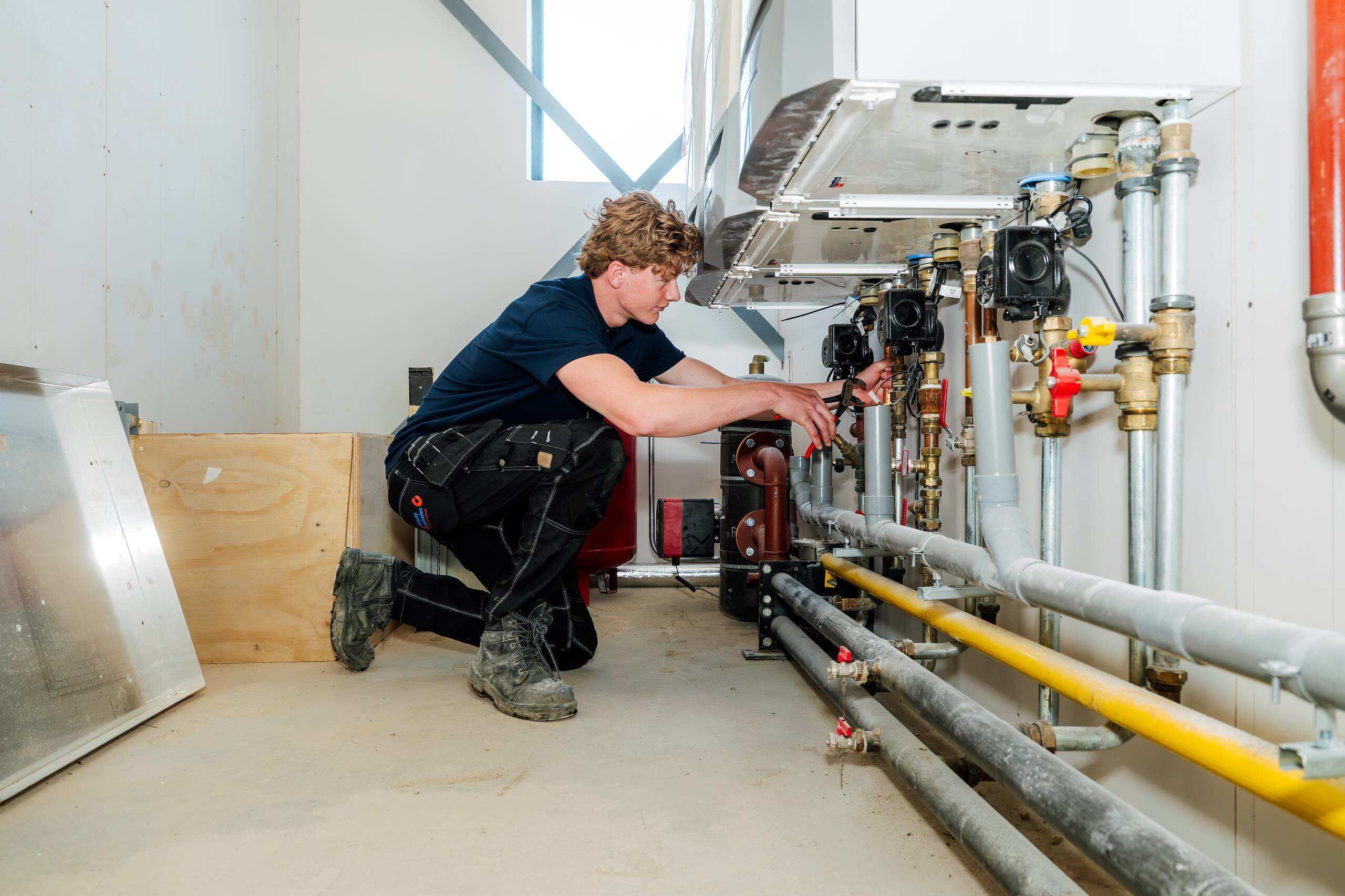 Servicetechnicus werkt aan leidingwerk en pompen in een technische ruimte