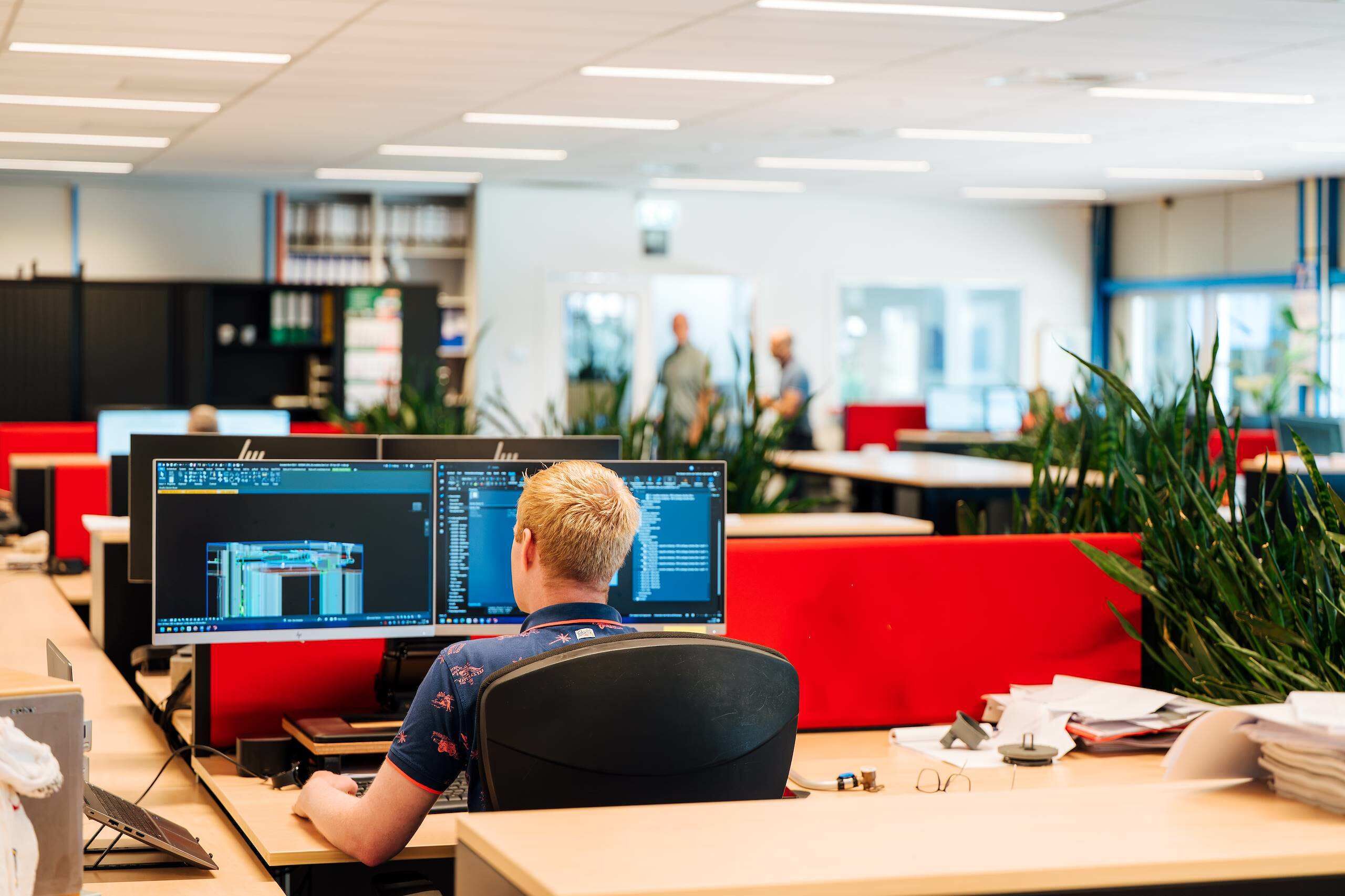 Engineer aan het werk achter twee beeldschermen op kantoor